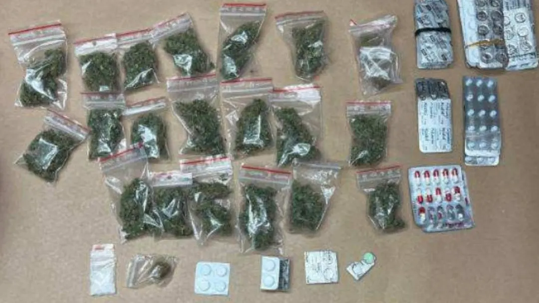 Bilden visar beslagtagna narkotika, inklusive påsar med cannabis och olika typer av tabletter, som kopplas till ett kriminellt nätverk enligt polisens utredning.
