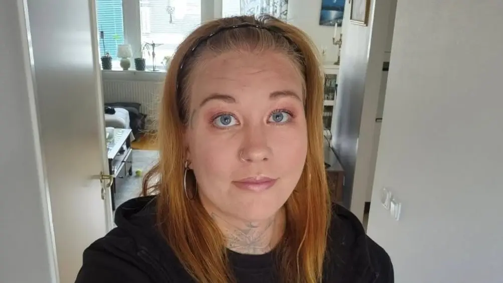 Gabi Mattsson står i ett hemmiljö med ljus inredning.