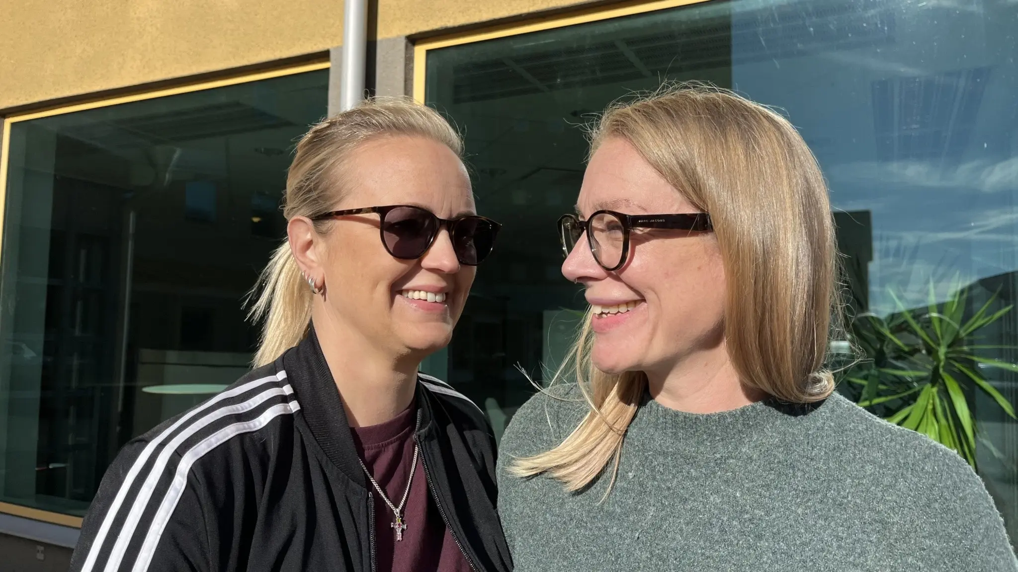 Ida Ljungkvist och Maria Pedersson står bredvid varandra utomhus framför ett fönster. 