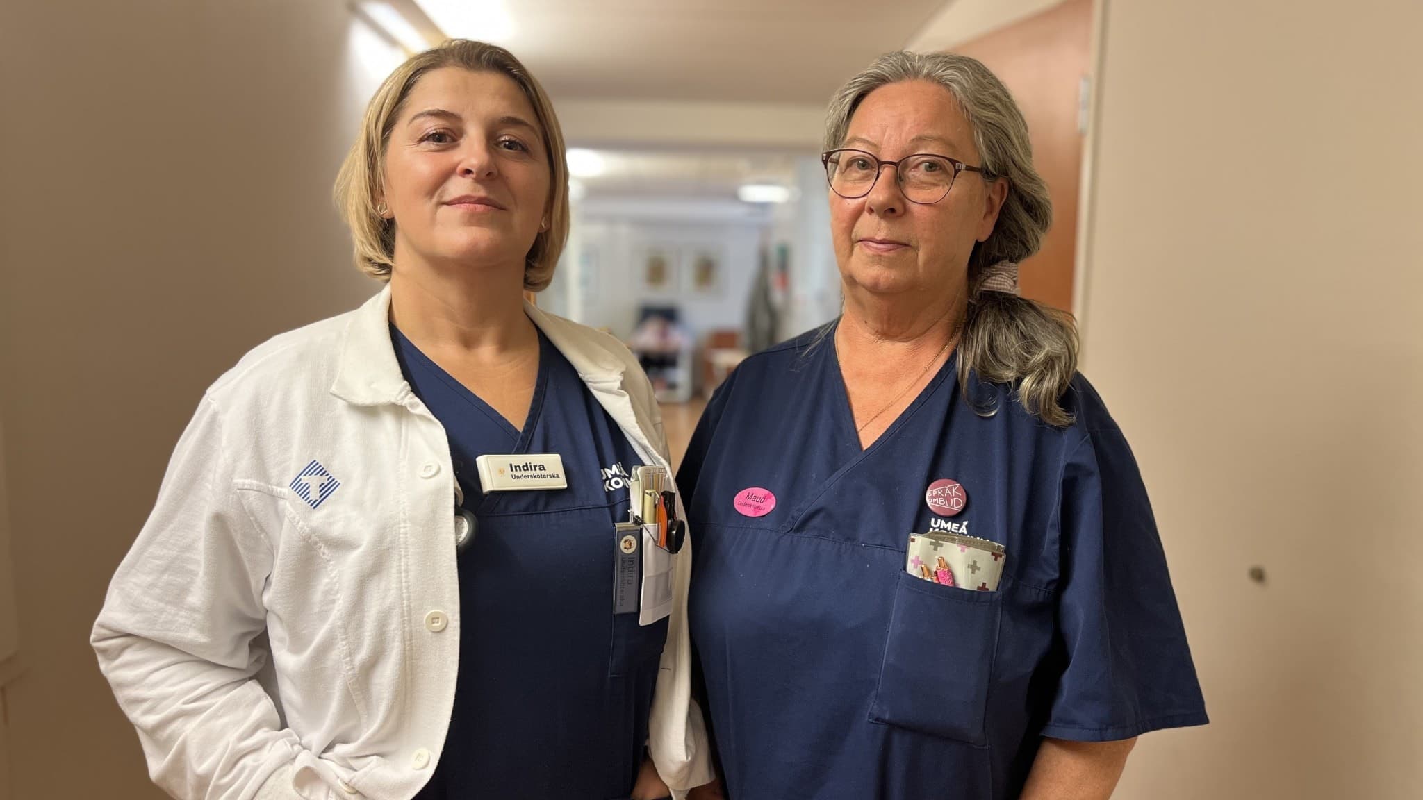 Maud Moström Andersson och Indira Kunalic, undersköterskor på Dragonens äldreboende, står tillsammans i en korridor iklädda arbetskläder och namnskyltar.
