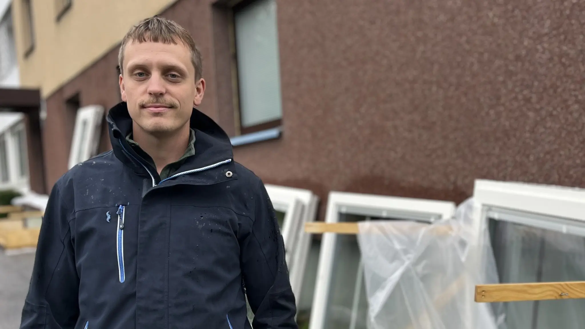 Pontus Andersson, platschef på saneringsföretaget Ocab i Sundsvall och Kramfors, står framför ett bostadshus där flera fönster har tagits bort och står lutade mot väggen.
