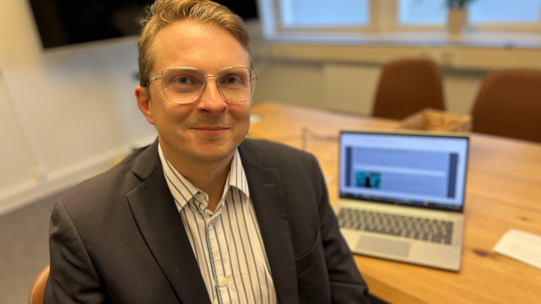 Patrik Jonasson, IT-säkerhetsexpert, sitter vid ett bord med en bärbar dator som visar en skärm. Han varnar för riskerna med att använda Windows 10 utan framtida uppdateringar.