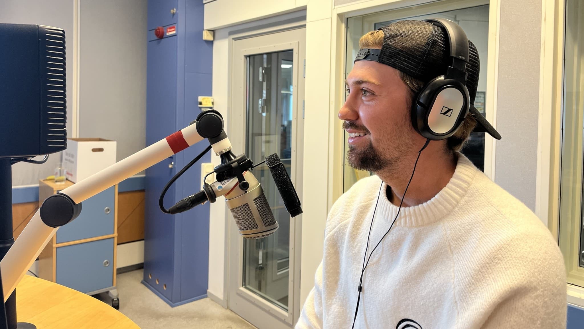 Hannes Hedlund från Kungsbacka sitter i en radiostudio med hörlurar och mikrofon framför sig, iklädd en vit tröja. Han livestreamar ofta via Twitch.