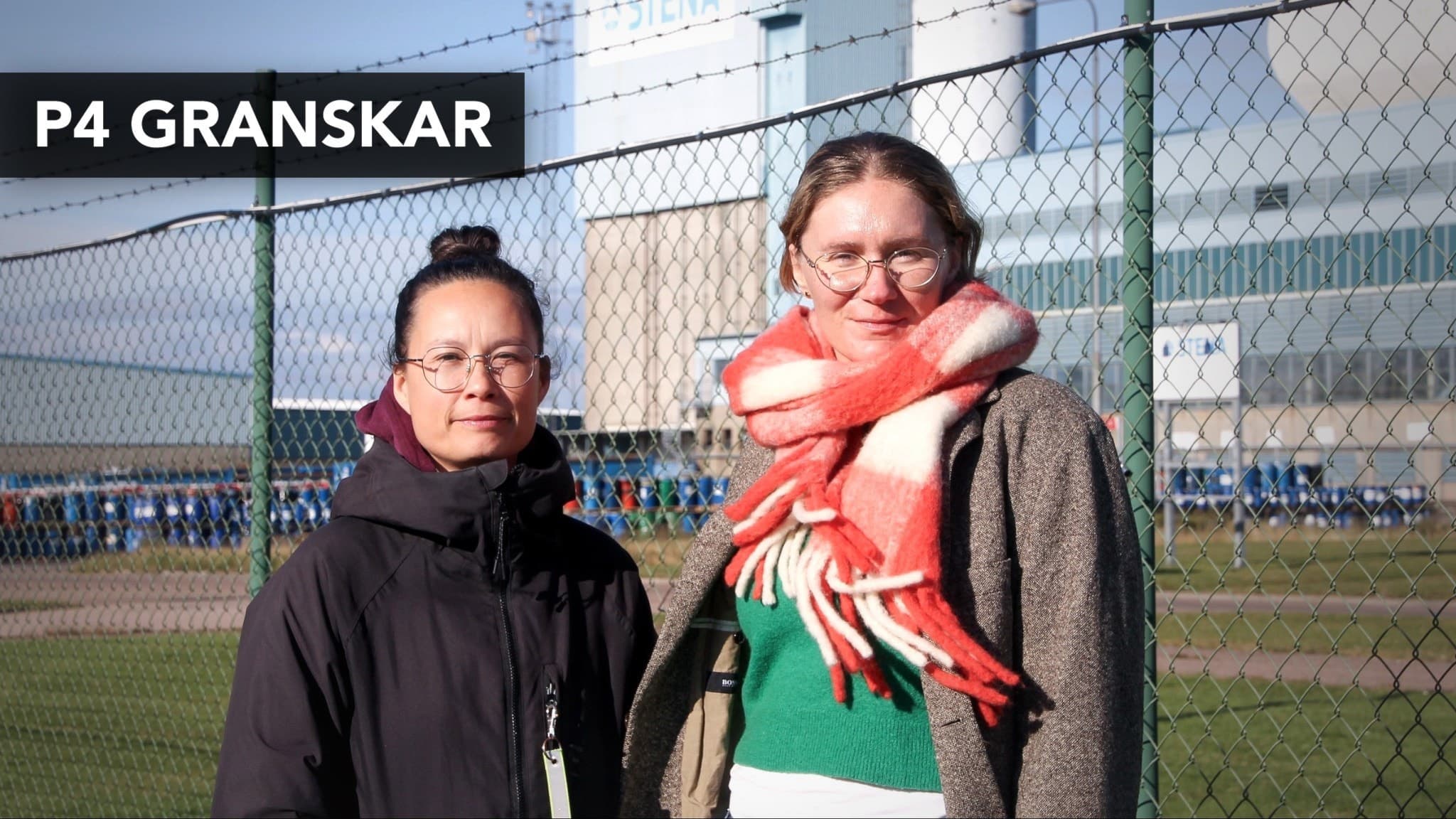 Reportrarna Sao-Mai Dau och Alma Tallborn Aringskog står framför ett stängsel med en industriell byggnad i bakgrunden. De granskar hanteringen av metallavfall.
