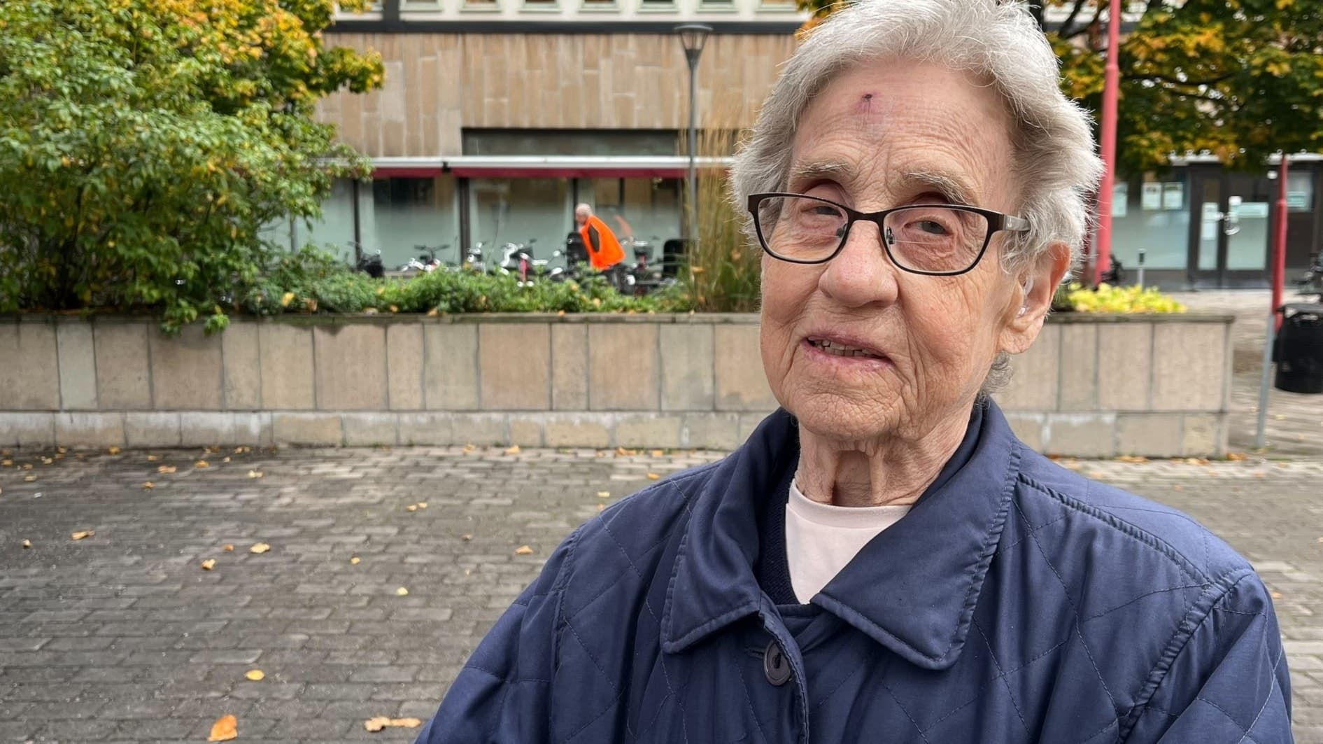 Anita Jansson står utomhus i en stadsmiljö i Örebro, iklädd en mörkblå jacka, efter att ha fått sina sprutor mot influensa och Covid-19 på en vaccinationsmottagning.