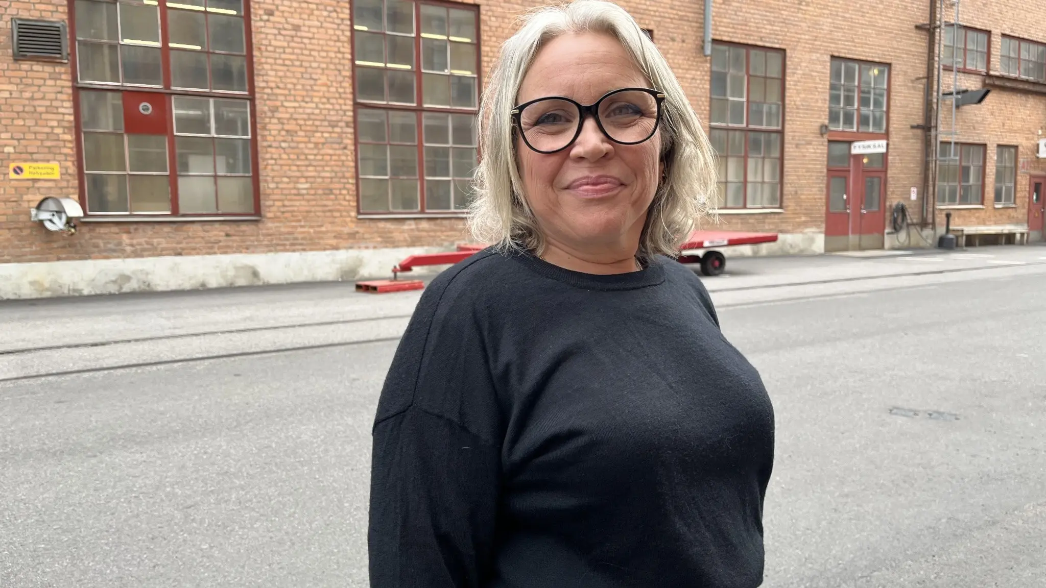 Anna-Karin Larsdotter, transportchef på Hitachi Energy, står utomhus framför en tegelbyggnad i Ludvika. Hon bär en mörk tröja och är fotograferad på en industrigata.