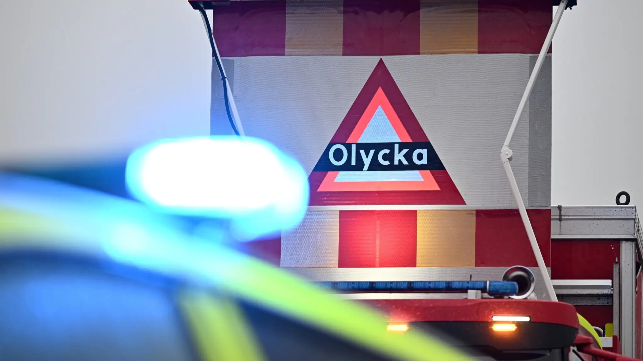 Varningstriangel på räddningstjänstbil med texten olycka samt blåljus på polisbil.