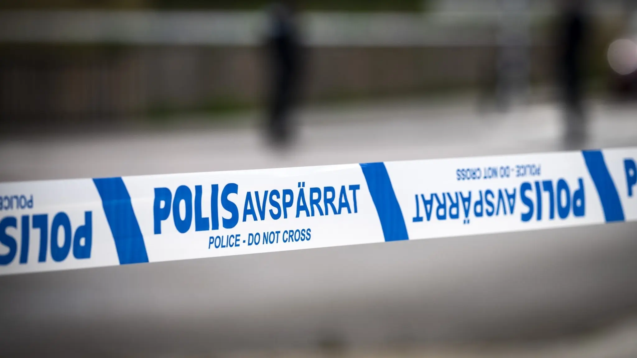 Blåvitt avspärrningsband från polisen utomhus. Suddig gata i bakgrunden.