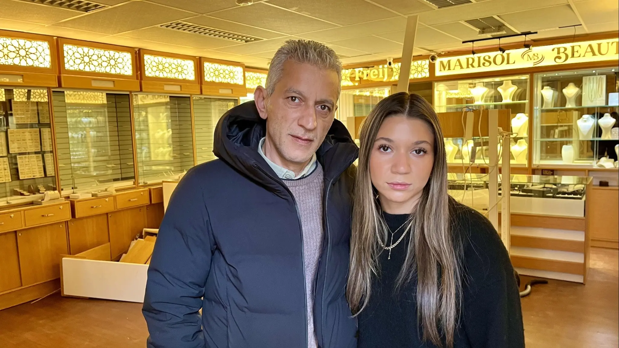 Aminah Frej och pappa Ghassan Farij står inne i sin guldbutik i Avesta efter en smash and grab-kupp, med tomma montrar och skadad inredning i bakgrunden.