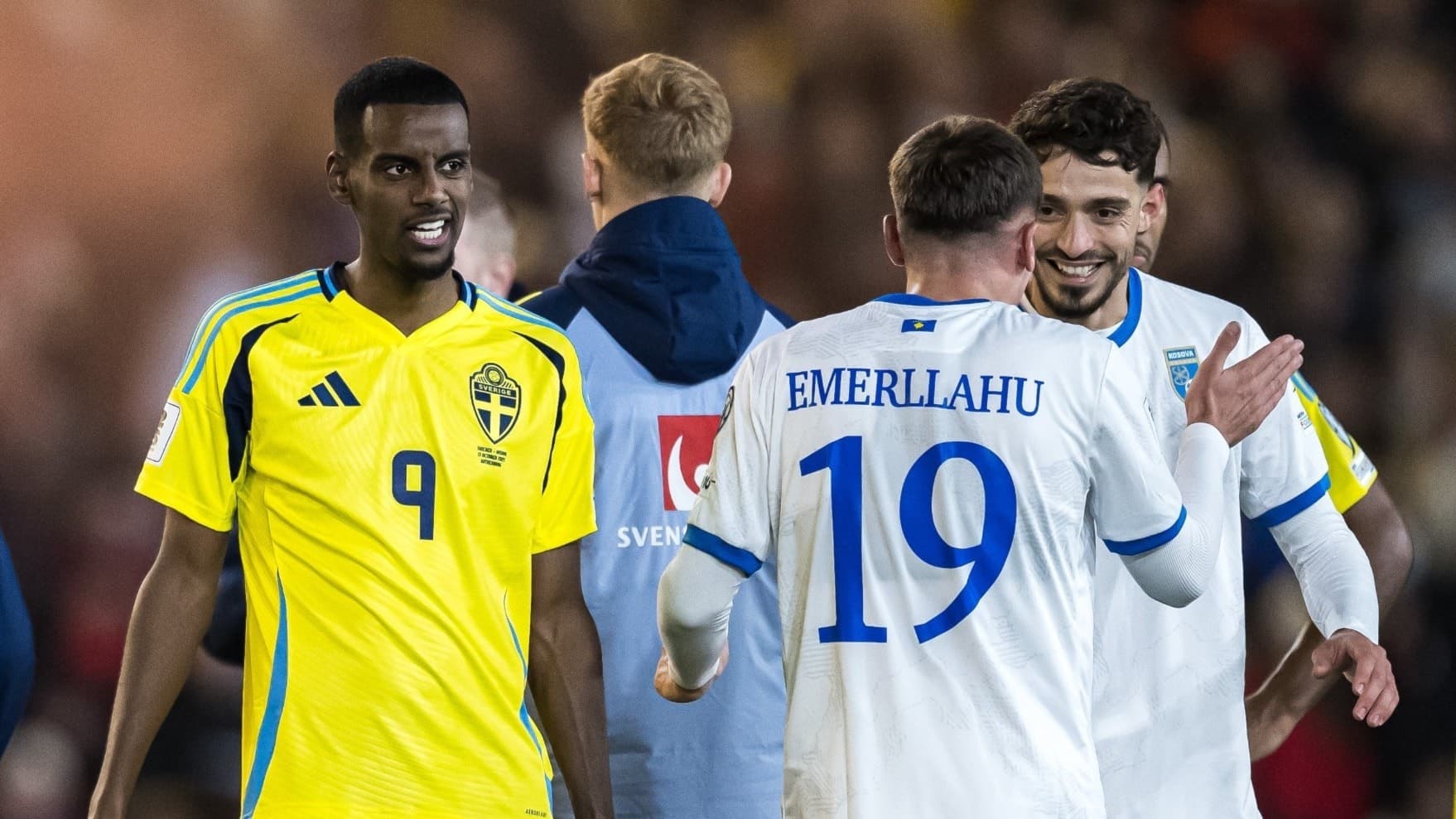 Svensk fotbollsspelare i gul landslagströja med nummer 9 står mot en motspelare från Finland i vit tröja med nummer 19 under en match, omgivna av andra spelare och tränare.