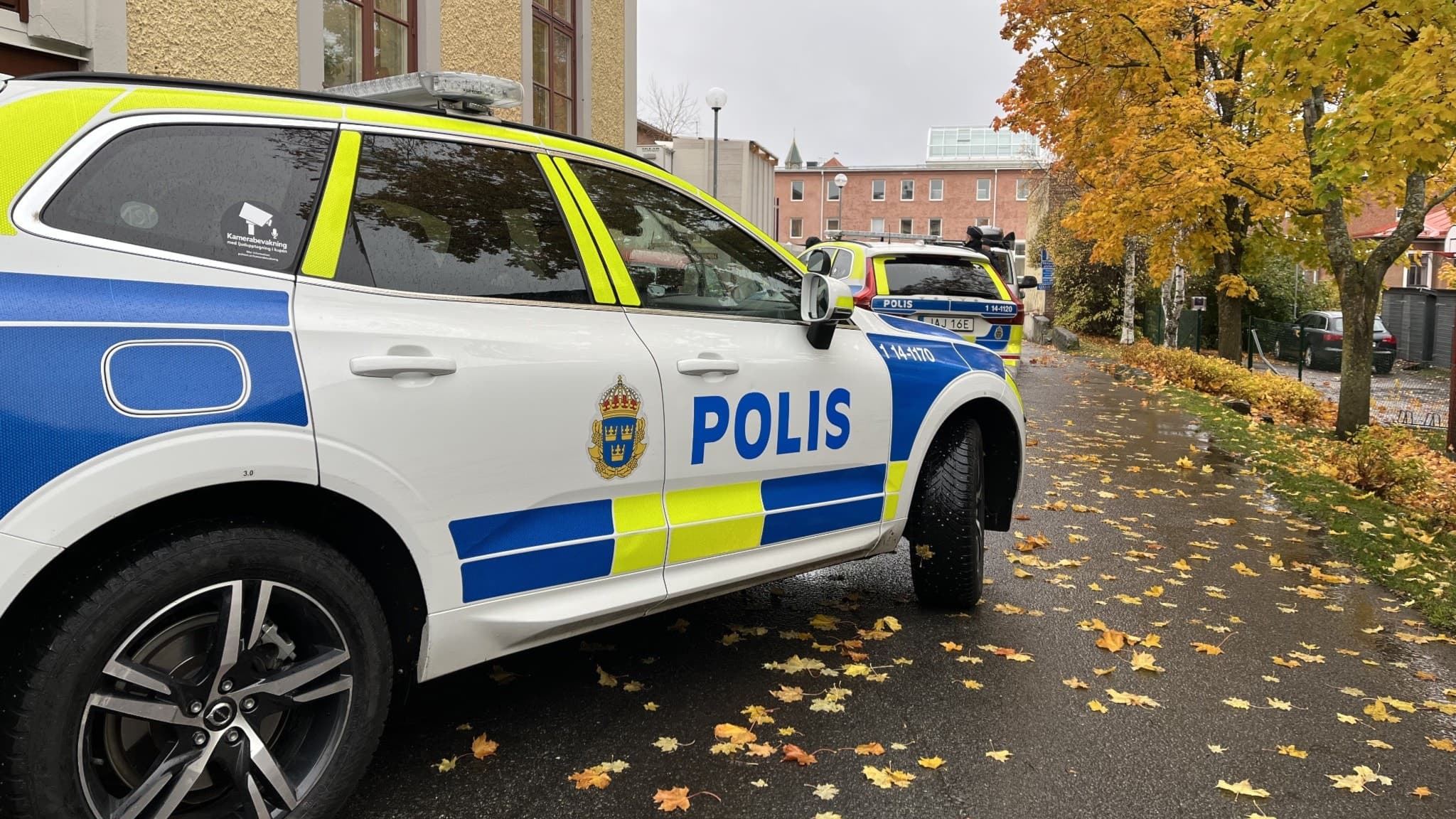 Polisbilar parkerade intill en gul byggnad.