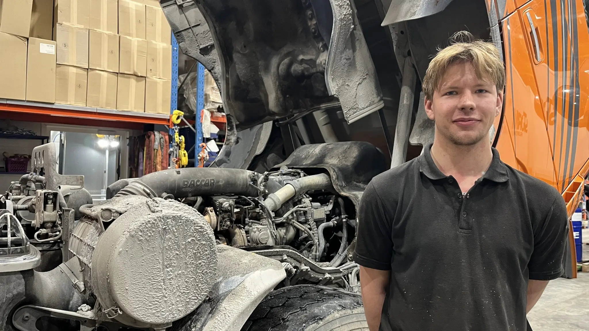 Joel Lilja, bilmekaniker i Brunflo, står framför en lastbil i en verkstad.