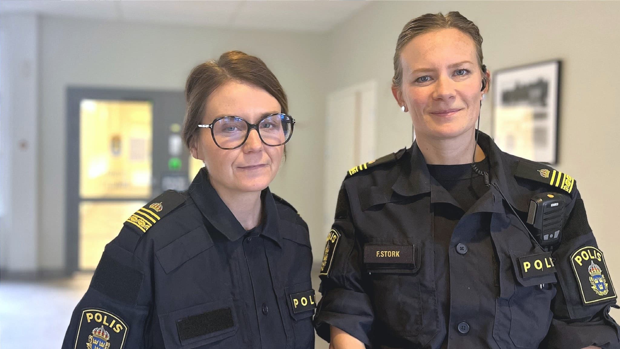 Kristine Eliasson och Frida Stork, gruppchefer i polisområde Jämtland, står i en ljus korridor iklädda polisuniformer med gula detaljer och polisens emblem på axlarna.