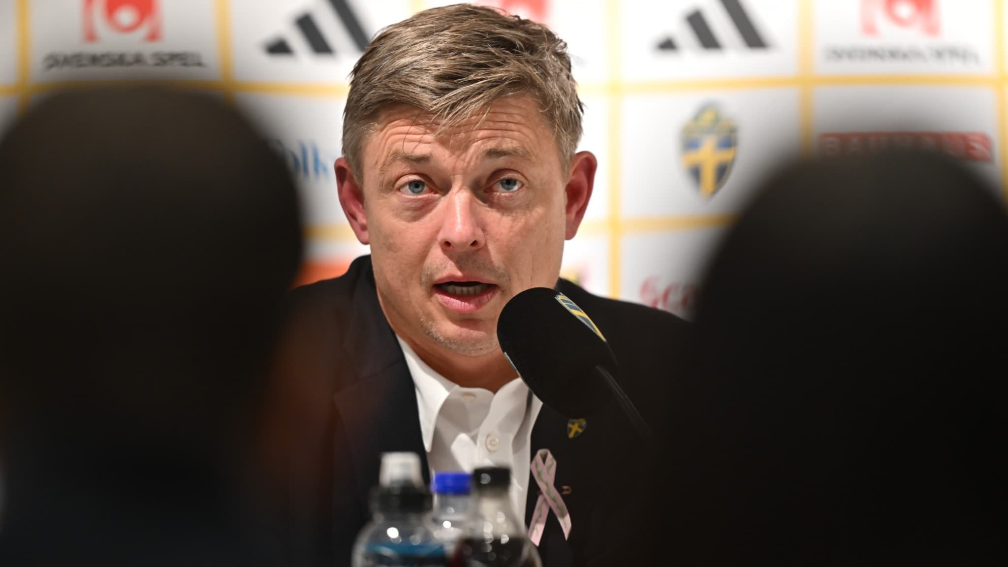 Sveriges förbundskapten Jon Dahl Tomasson sitter vid ett bord under en pressträff efter VM-kvalmatchen mellan Sverige och Kosovo på Ullevi i Göteborg. Vattenflaskor syns på bordet.