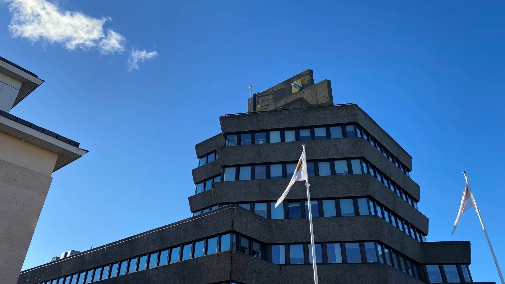 Ett brunt hus med långa rader av fönster. Längst upp finns Vetlandas kommunvapen i gult och blått.