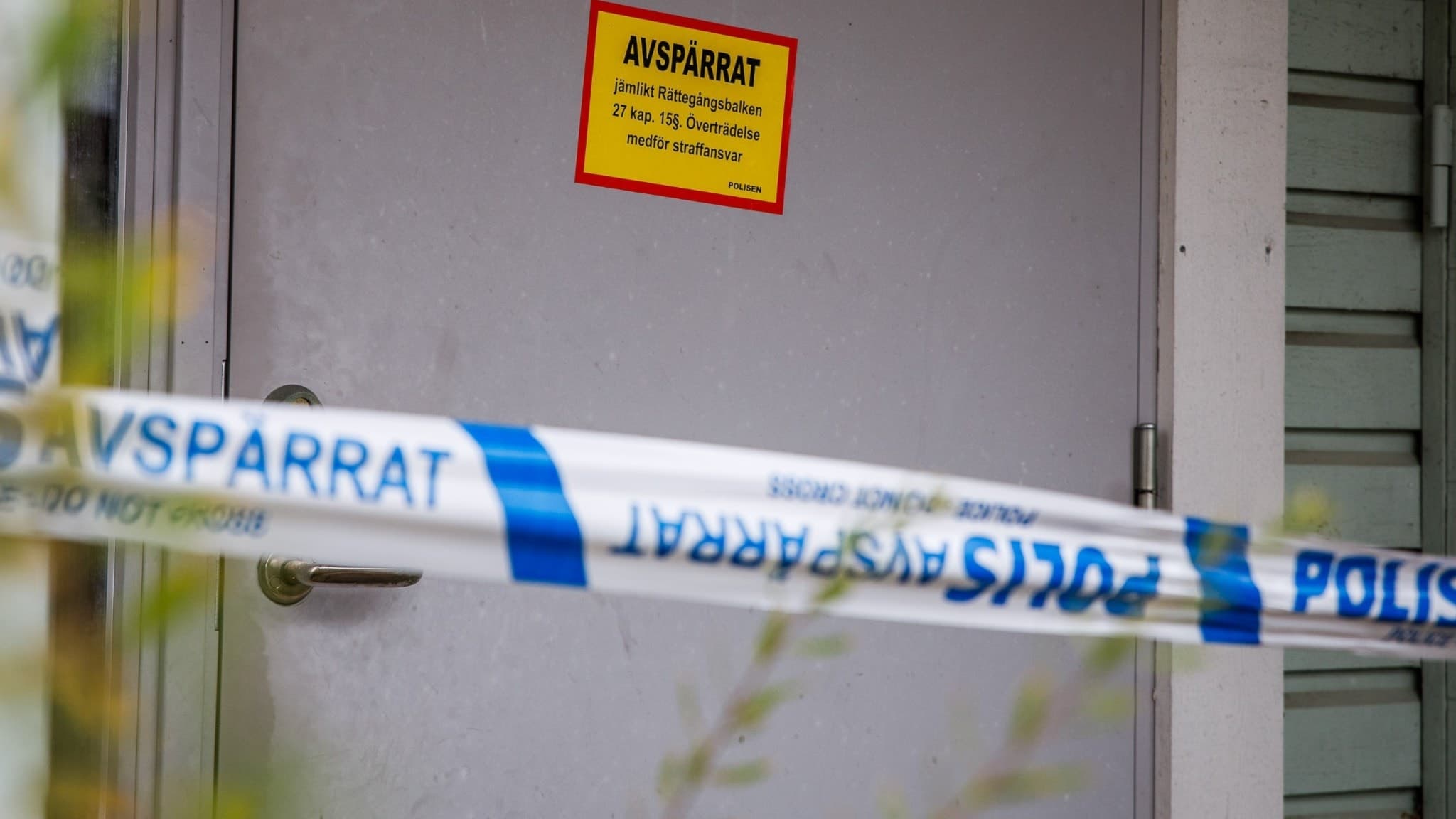 En avspärrad dörr med polisens blåvita avspärrningsband i Tenhult, där ett misstänkt mordförsök har skett. En gul skylt med röd ram varnar för obehörig tillträde.