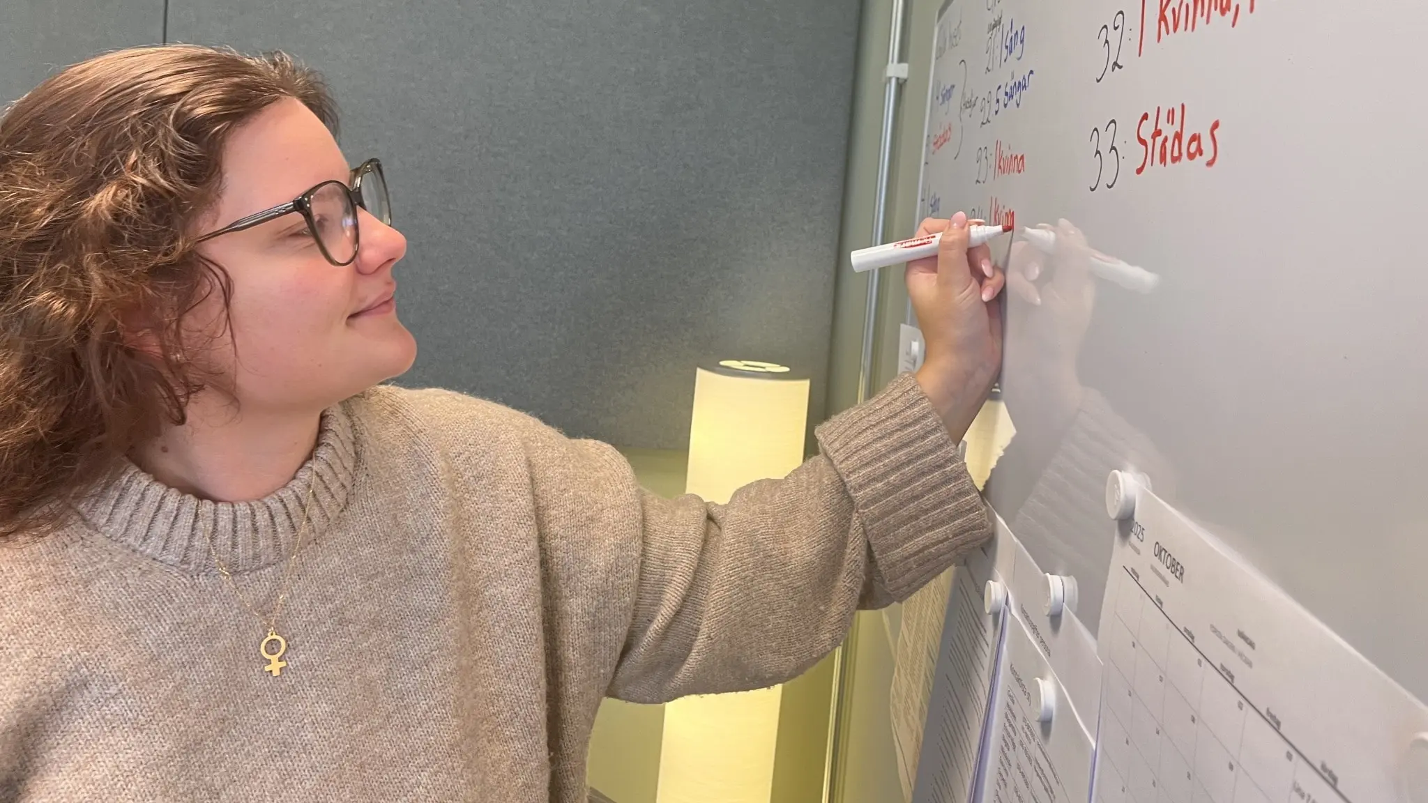 Kvinna skriver på whiteboard-tavla