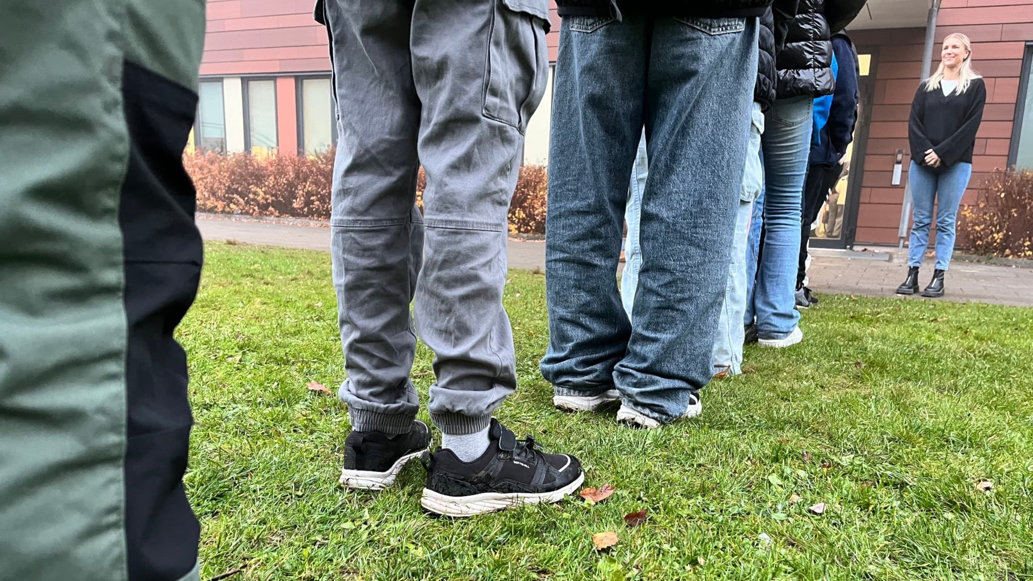 Elever på Bodaskolan i Borås står på led utomhus på gräs framför skolbyggnaden. Läraren Helena Rydebo syns i bakgrunden och beskriver hur detta skapar en lugnare start i klassrummet.