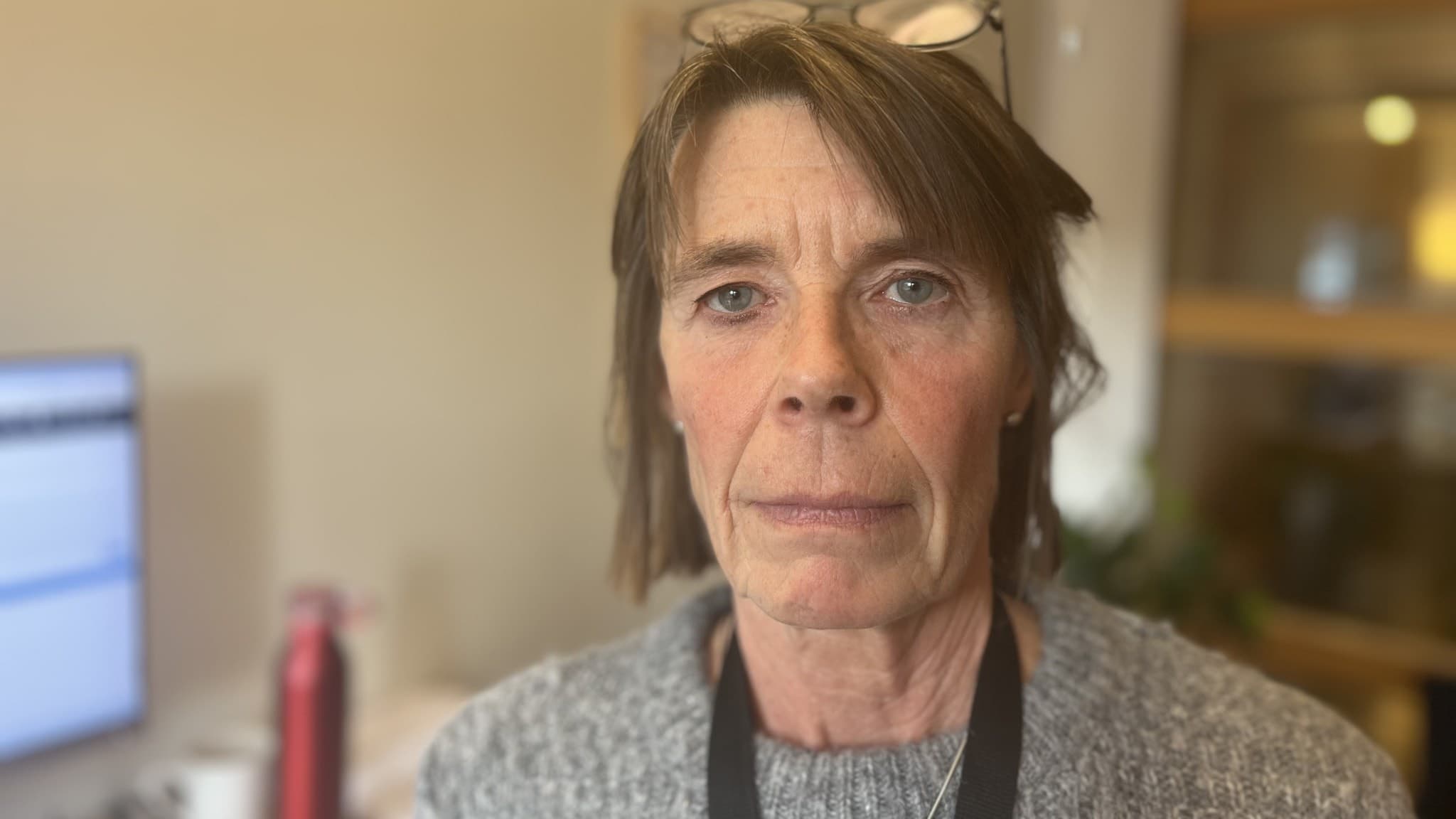 Katarina Eriksson, konsumentrådgivare vid Borås Stad, står inomhus framför en datorskärm med dokument öppna, iklädd en grå tröja och glasögon på huvudet. 