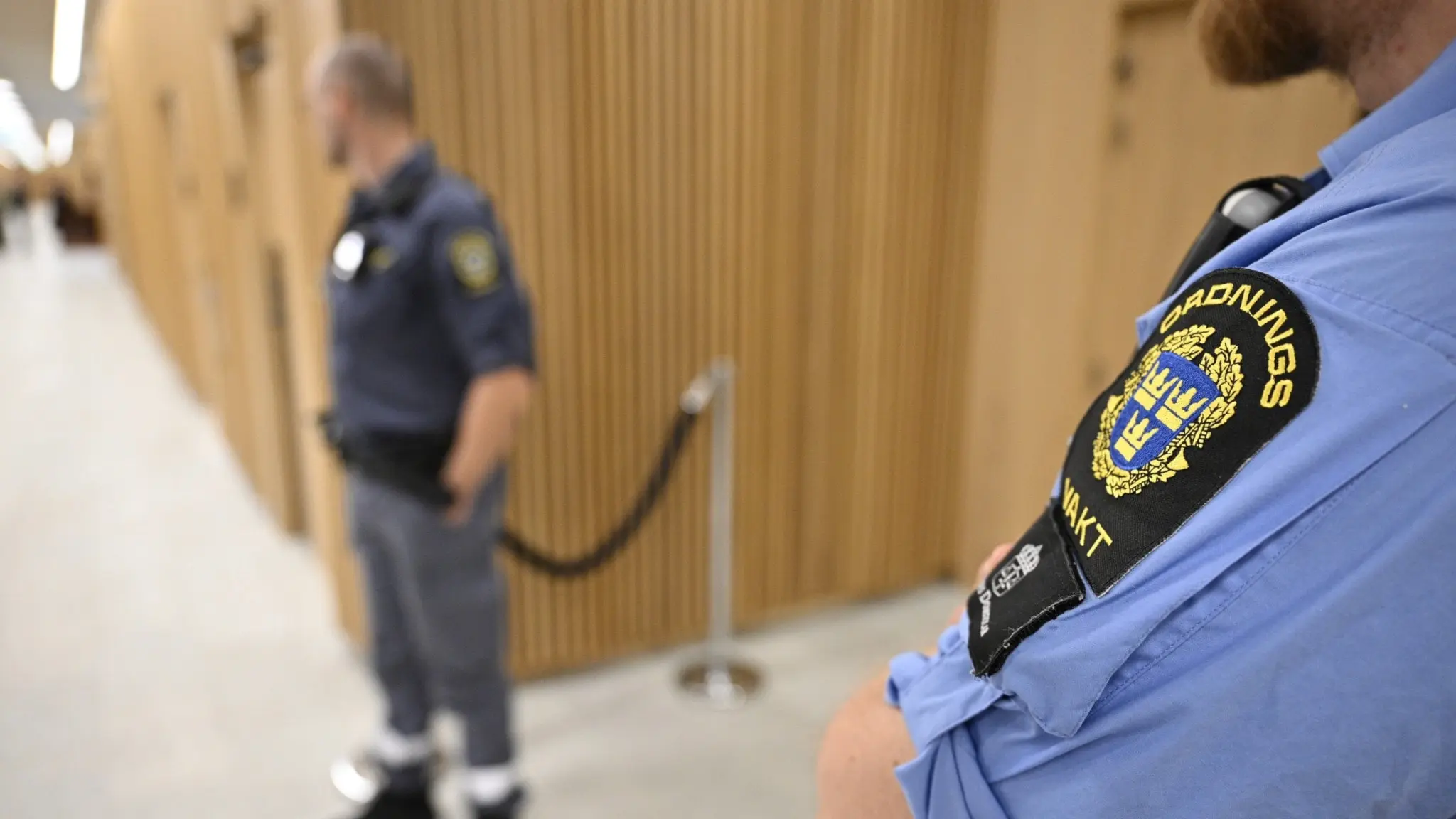 Bild inifrån Malmö tingsrätt med två ordningsvakter som står utanför ett rum med stängda dörrar.