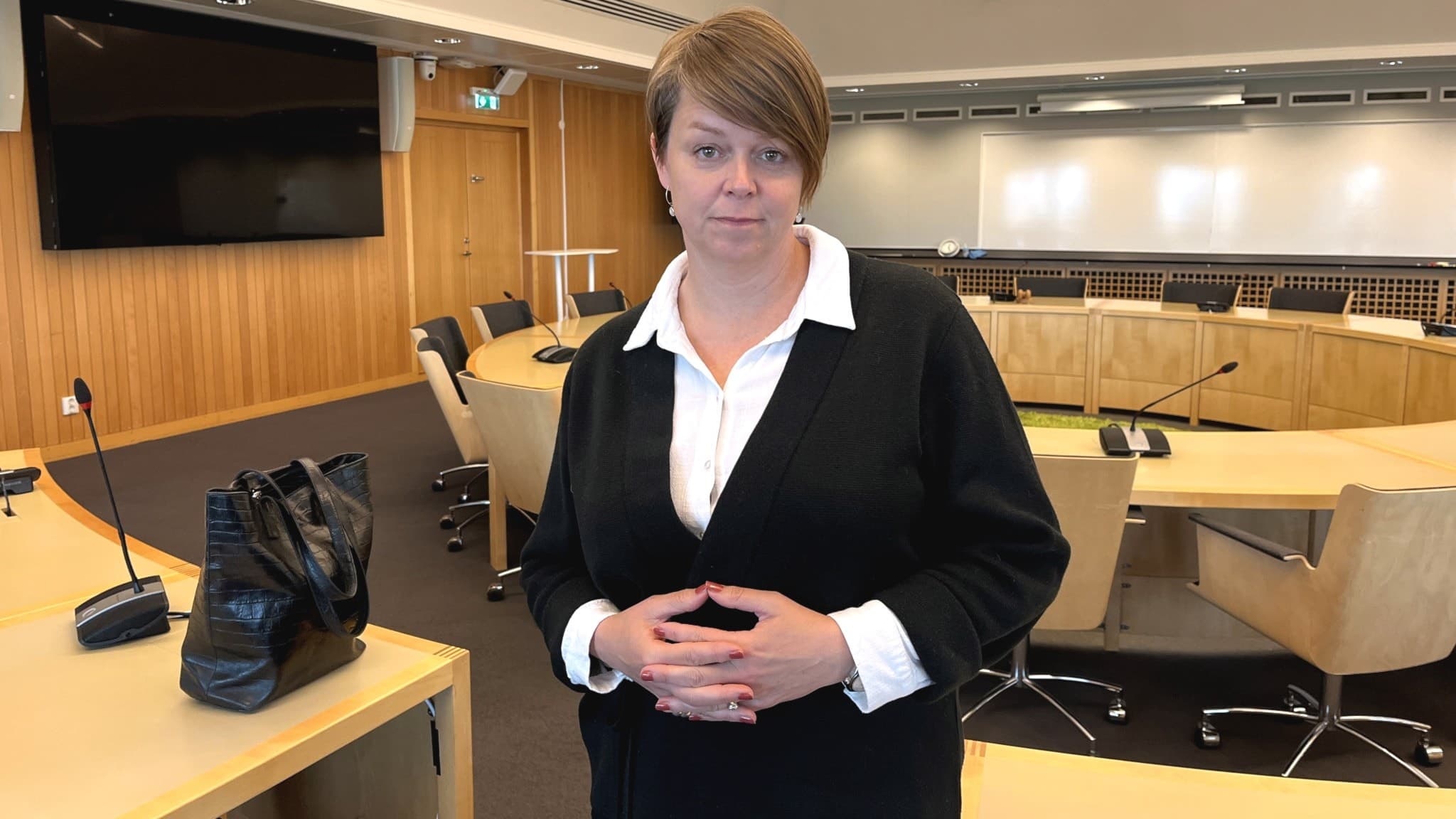 Kvinna med vit skjorta svart tröja i en möteslokal