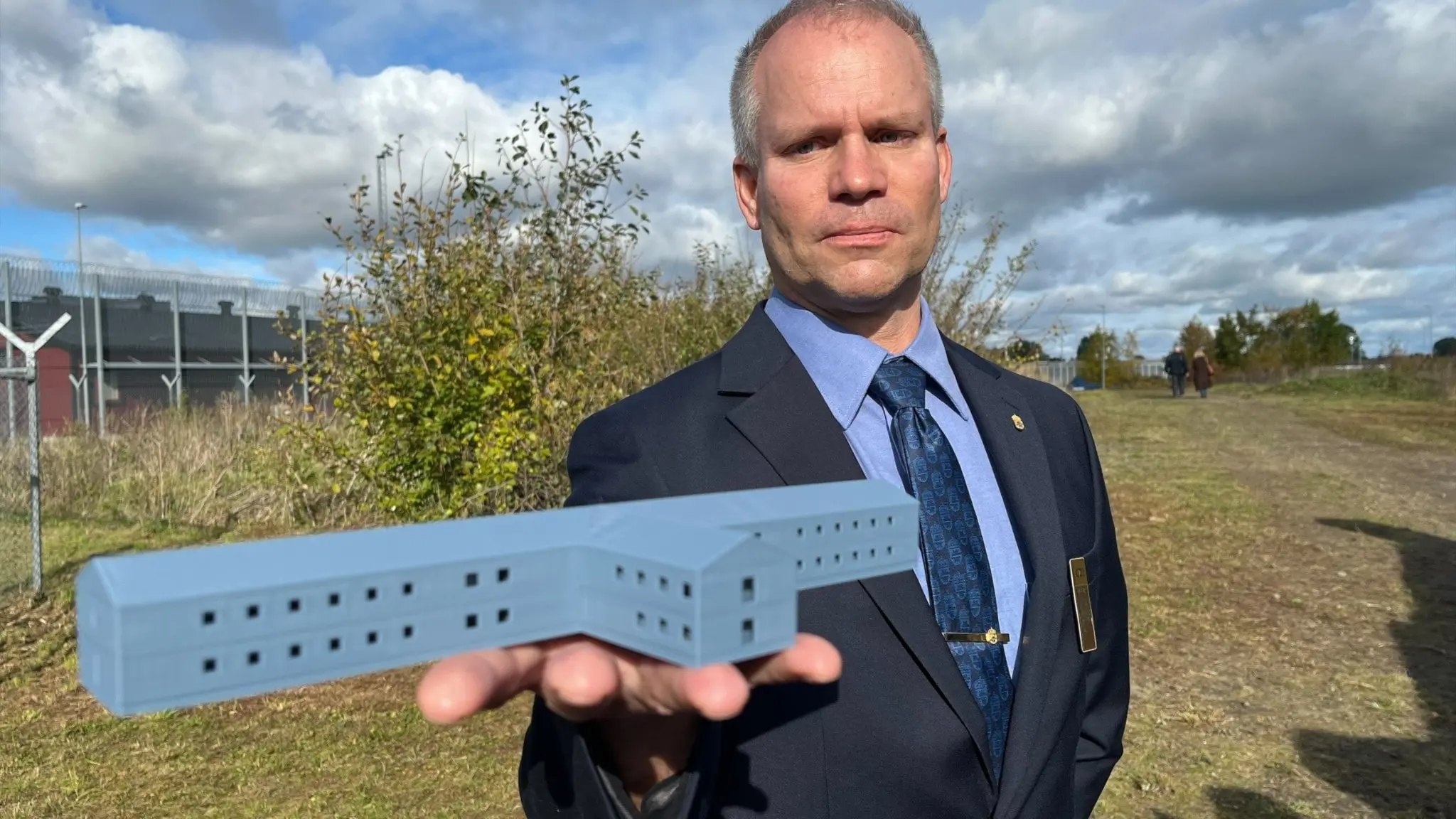 En kriminalvårdschef håller i en modell av den nya fängelsebyggnaden. 