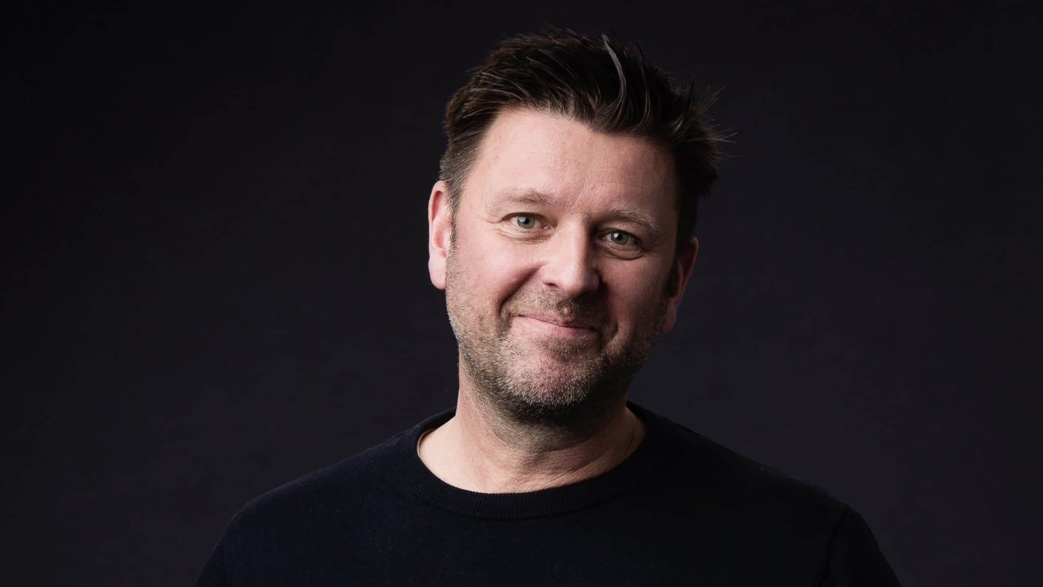 André Widenrot, mäklare i Boden, poserar framför en mörk bakgrund. Han bär en svart tröja och står i ett porträttformat.