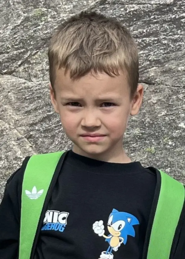 Barnen Tage, 6 år, och Stella, 9 år, berättar att de hade vildsvin hemma på tomten. Här står de framför en stenklippa.