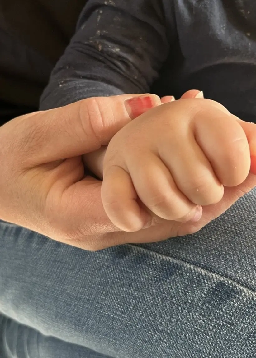 En anonym bild på en mamma som håller sin ettåring i handen. 