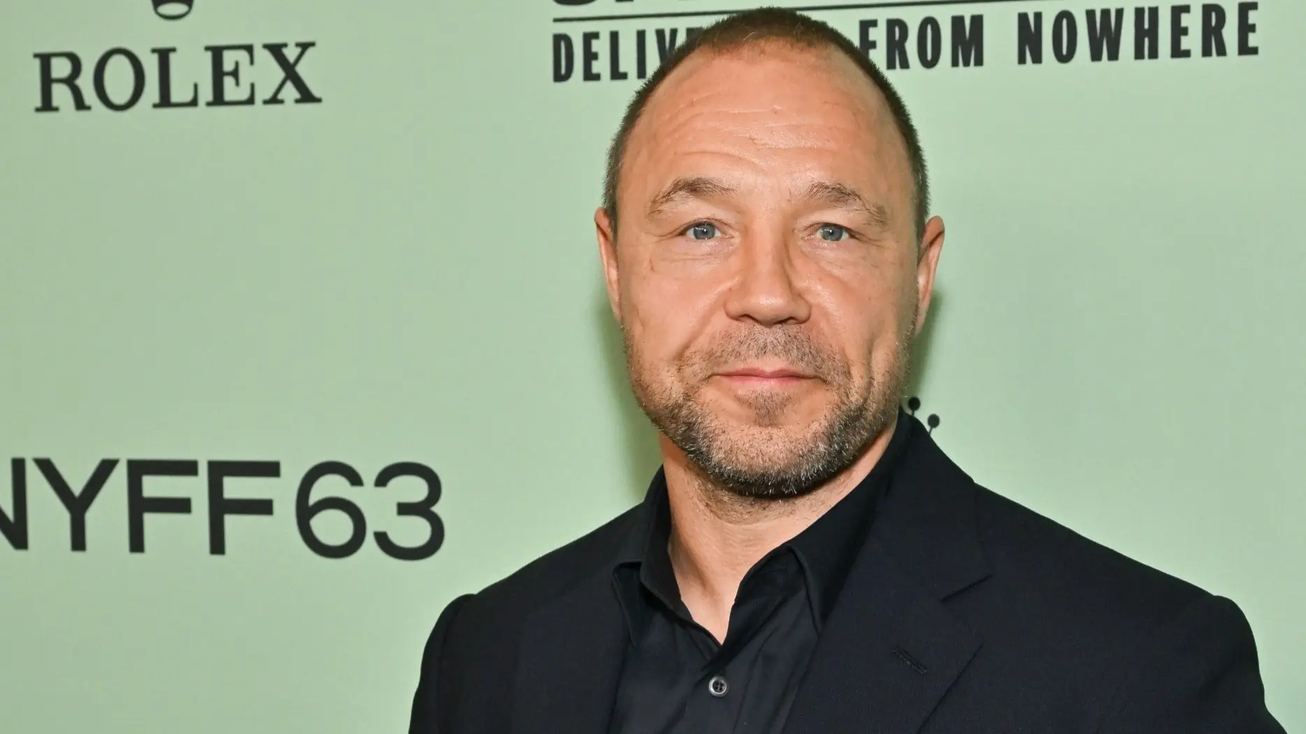 Stephen Graham står framför en mintgrön bakgrund med texten 'Springsteen: Deliver Me From Nowhere' och 'NYFF63' vid premiären av filmen under New Yorks filmfestival.