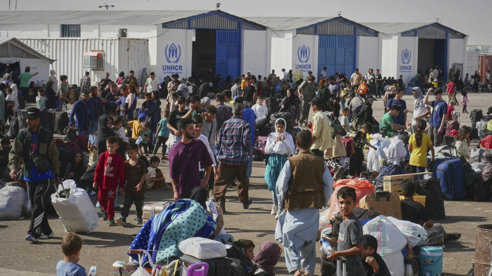 Afghanska flyktingar som återvänt från Iran samlas vid ett UNHCR-center nära Islam Qala-gränsövergången i Heratprovinsen, Afghanistan. Många bär bagage och väntar på hjälp.
